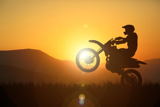 Silhouette of a motocross motorcycle lifting the front wheel. Adventure and Action Concepts photo