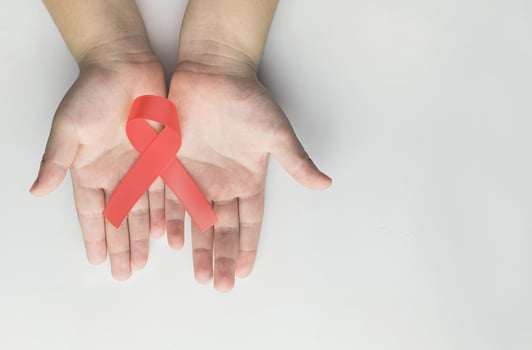 Kid hands holding red AIDS awareness ribbon. Aids Awareness photo