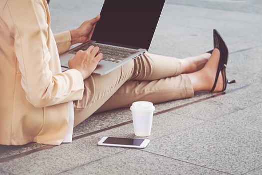 Businesswoman in high heels sitting on floor with computer in her lap photo