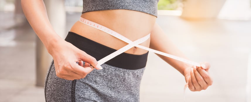 young woman measuring her waist with a tape measure photo