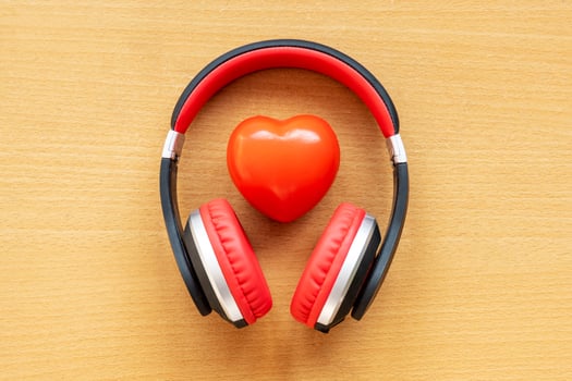 Headphones and red heart on wooden desk. Musical concept photo