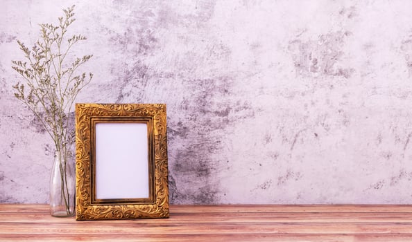 Picture frame with flowers on wall background and wooden table. Poster product design styled photo