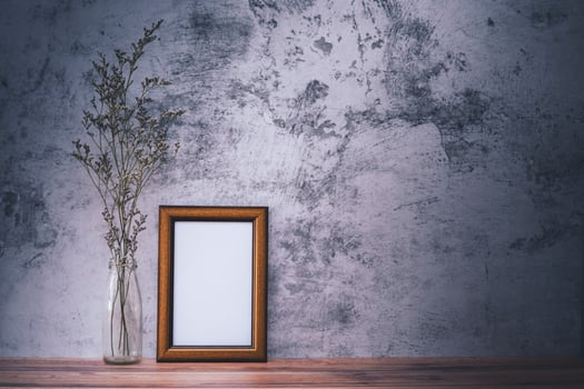 Picture frame with flowers on wall background and wooden table. Poster product design styled photo