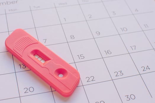Pregnancy test on calendar background, health concept photo