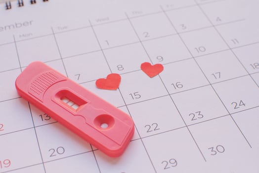 Pregnancy test on calendar background, health concept photo