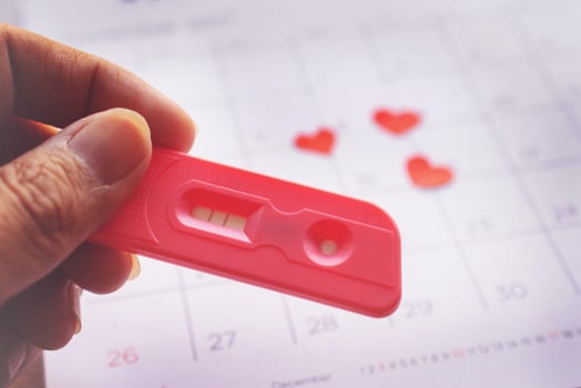 Pregnancy test on calendar background, health concept photo
