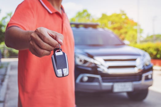 Man holding car keys with car on background photo