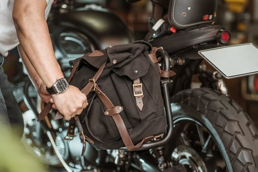 rider install a motorcycle saddlebag or side bag on luggage bracket  vintage motorbike. motorcycle travel concept. selective focus photo