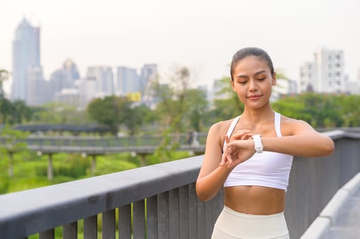 A young fitness woman in sportswear using smart watch while exercising in city park, Healthy and Lifestyles. photo