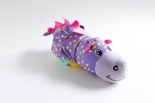 Plush soft children's toy purple dragon with colorful round spots. Turn it inside out. White background, space for text photo