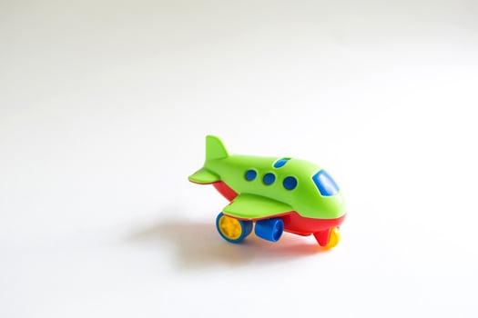Toy green plastic airplane with colored red, blue, yellow details on a white background. Toy for a child, the concept of tourism and travel, air travel. Space for text photo