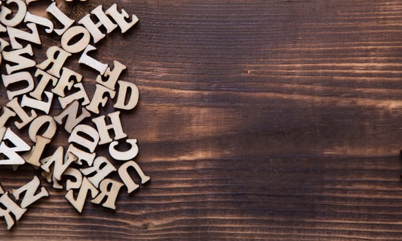 Letters of the English alphabet on a dark wooden background. The concept of education, word games, needlework. Space for text photo