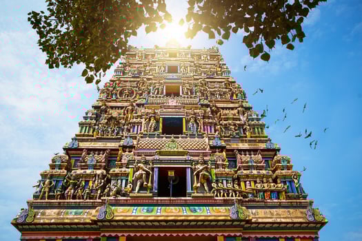 Traditional Hindu temple Kidangamparambu Sree Bhuvaneswari in India in Allapuzha Allepi Kerala. Tall building with colorful figures of Indian mythology and gods, flock of live birds. Tourism, travel photo