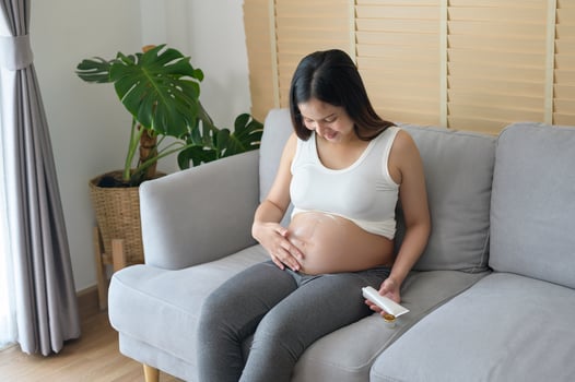 Young pregnant woman applying moisturizing cream on tummy, healthcare and pregnancy care photo