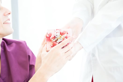 Doctor giving a gift box to patient in a wheelchair. photo