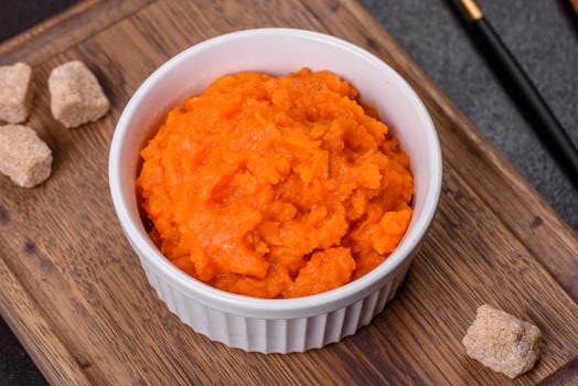 Pumpkin carrot baby puree in bowl on a dark background photo