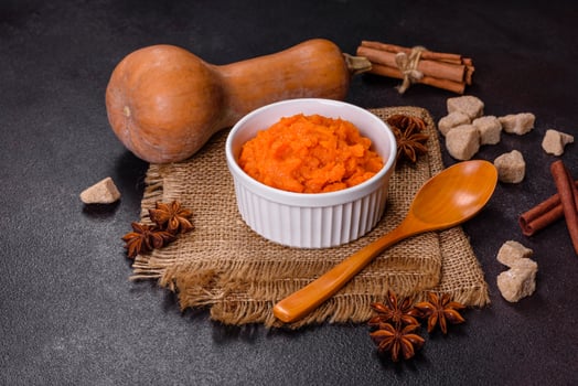 Pumpkin carrot baby puree in bowl on a dark background photo