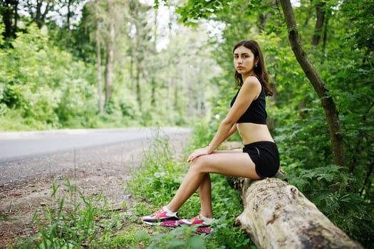 Sport girl at sportswear having rest in a green park after training at nature. A healthy lifestyle. photo