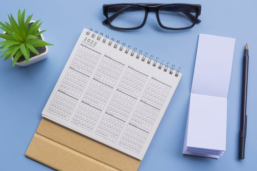 Notepad with 2022 calendar, glasses, pen and potted plant on a desk. Flat lay photo