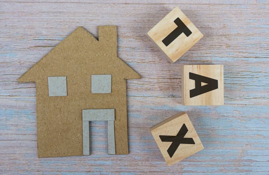 Paper House Model Near Wooden Blocks With Tax Text On Wooden Background photo