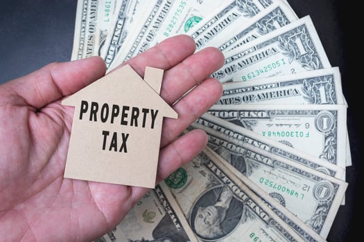 Property tax text on brown paper house model with background of dollar banknotes photo