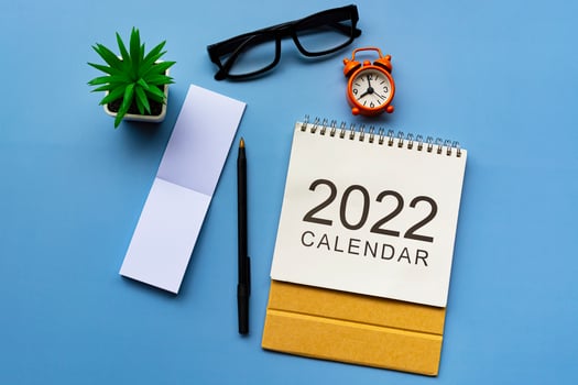 Notepad with 2022 calendar, glasses, pen, potted plant and alarm clock. photo