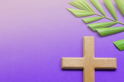 Cross and palm leaves on purple background. Lent season concept. photo