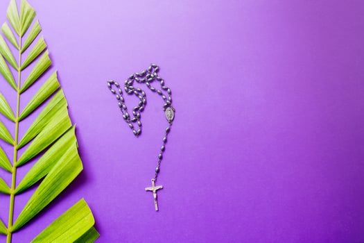 Cross and palm leaves on purple background. Lent season concept. photo