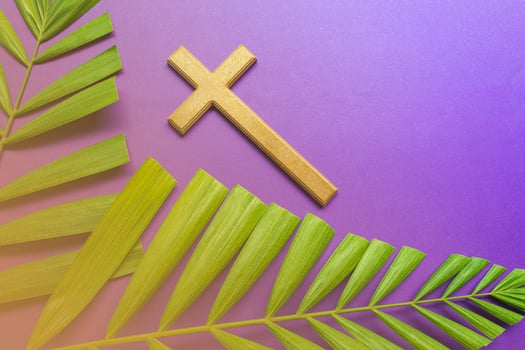 Cross and palm leaves on purple background. Lent season concept. photo