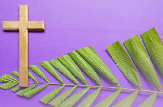 Cross and palm leaves on purple background. Lent season concept. photo