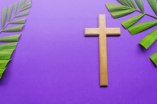 Cross and palm leaves on purple background. Lent season concept. photo