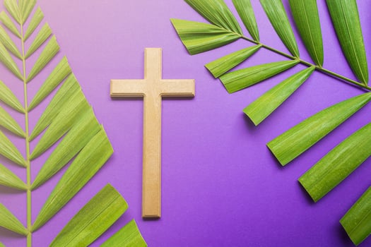Cross and palm leaves on purple background. Lent season concept. photo