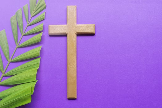Cross and palm leaves on purple background. Lent season concept. photo
