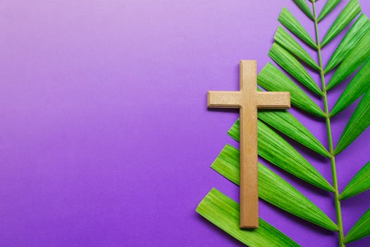 Cross and palm leaves on purple background. Lent season concept. photo