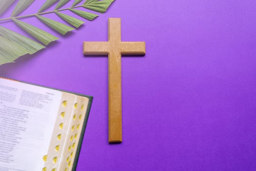 Cross and holy bible with palm leaves on purple background. Holy week concept. photo