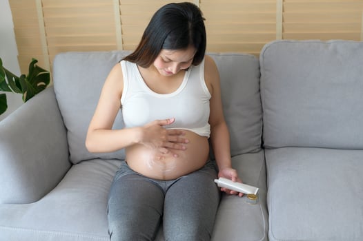 Young pregnant woman applying moisturizing cream on tummy, healthcare and pregnancy care photo