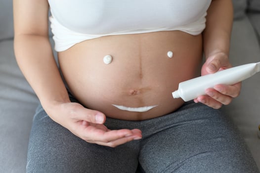 Young pregnant woman applying moisturizing cream on tummy, healthcare and pregnancy care photo