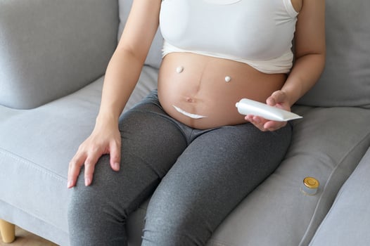 Young pregnant woman applying moisturizing cream on tummy, healthcare and pregnancy care photo