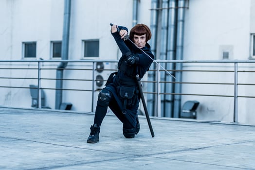 portrait of young redhead woman with japanese sword dressed in futuristic cyberpunk costume standing on the roof. photo