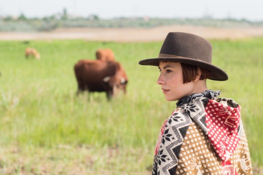 Young woman traveler in poncho and hat walk in the fields and farm photo