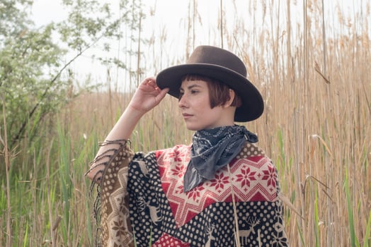 Young woman traveler in poncho and hat walk in the fields and farm photo