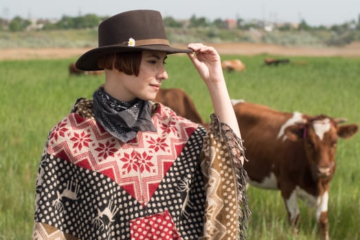 Young woman traveler in poncho and hat walk in the fields and farm photo
