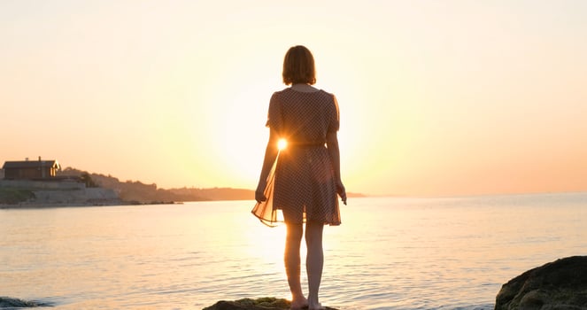 Young woman in dress relaxing on the summer beach during beautiful sunrise photo