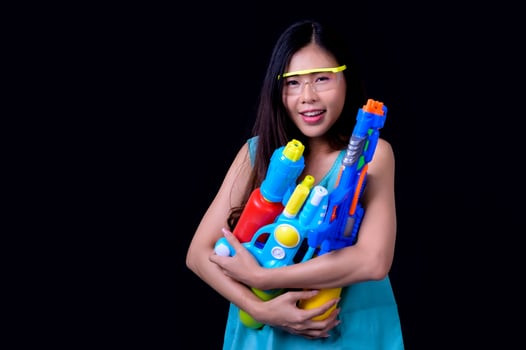 A beautiful Asian woman shows a gesture while holding a plastic water gun during the Songkran festival photo