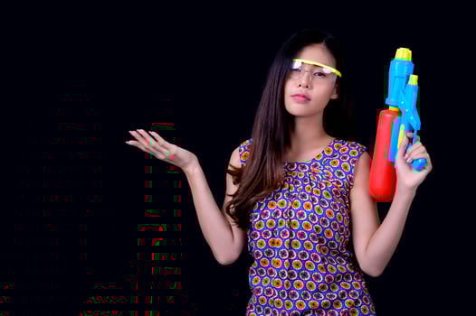 A beautiful Asian woman shows a gesture while holding a plastic water gun during the Songkran festival photo
