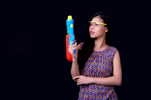 A beautiful Asian woman shows a gesture while holding a plastic water gun during the Songkran festival photo