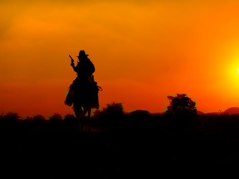 Western cowboys are sitting on horseback under the sun and preparing to use guns to protect themselves in a land that is not yet legal photo