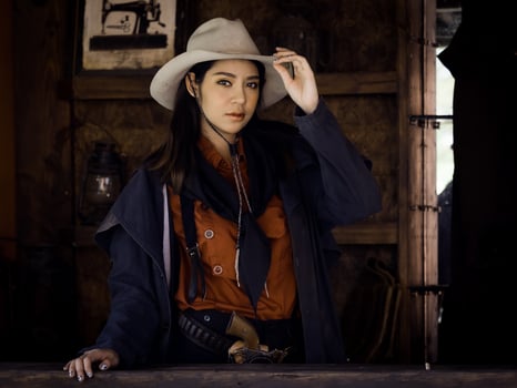 A Western cowgirl is preparing to use a gun to defend herself in a land where people must protect themselves photo