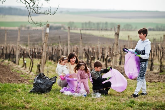 Family with trash bag collecting garbage while cleaning in the vineyards . Environmental conservation and ecology, recycling. photo