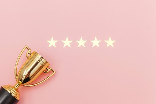 Simply flat lay design winner or champion gold trophy cup and 5 stars rating isolated on pink pastel background. Victory first place of competition. Winning or success concept. Top view copy space. photo